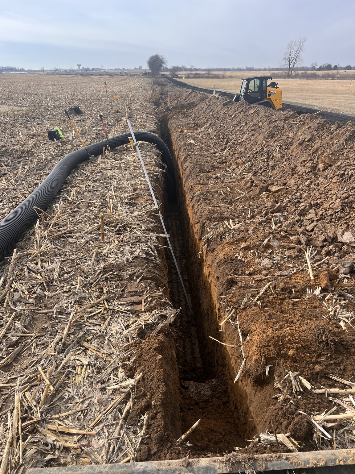 Deep utility trench and pipe installation through a farm field